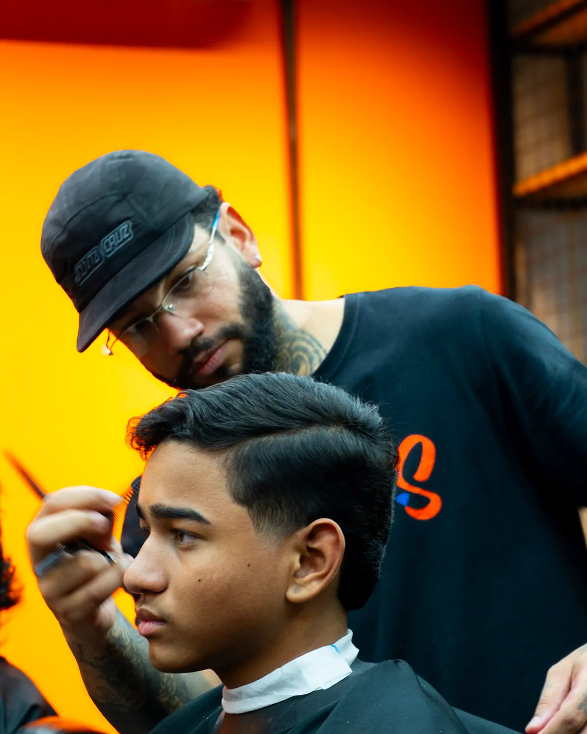 Barbeiro fazendo o acabamento do corte de um cliente