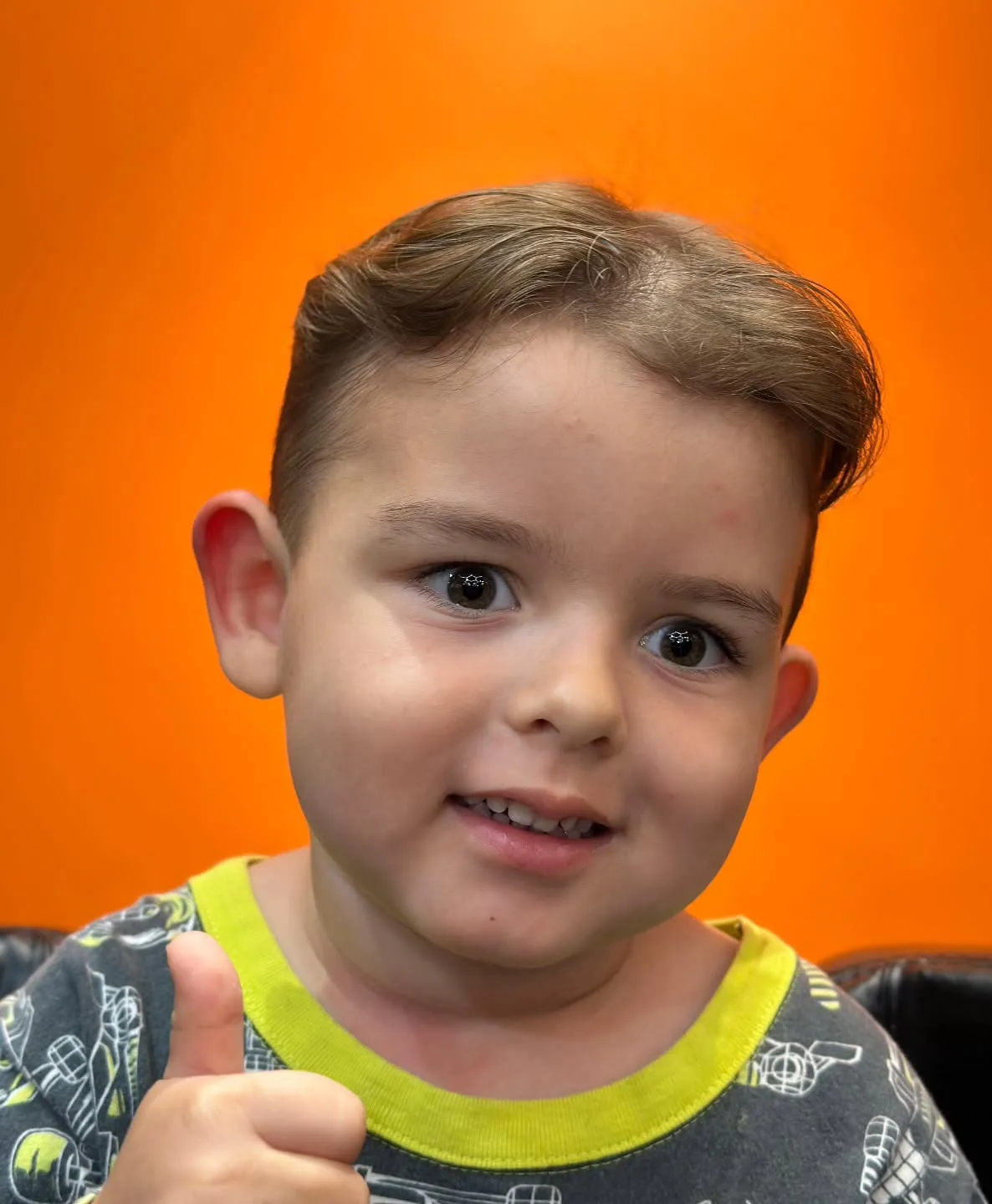 Menino sorrindo e fazendo joinha depois do corte infantil na Swarowski